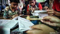 Para siswa tampak serius menggoreskan canting ke kain yang telah dipola.