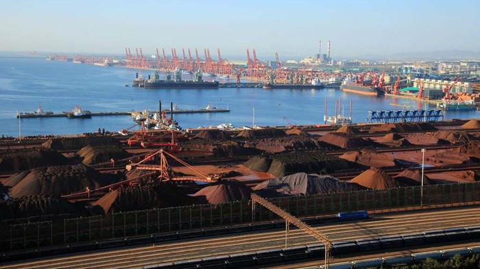 Biji besi dikumpulkan dengan cara ditumpul di Pelabuhan Rizhao, Shandong, Tiongkok, Senin (17/10/2022). Dari jauh terlihat bijih besi ini mirip padang pasir berwana hitam.