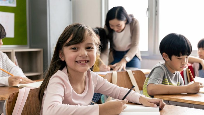 Portrait of Asian elementary school kids studying in a classroom. The girl smiled and looked at the camera. His classroom diversity