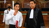 Bharada E menghadap ke kamera dan melambaikan tangannya sebelum sidang.