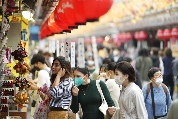 Foreign tourists take a rest over ice cream as they visit a promenade lined with souvenir shops leading to the Sensoji Buddhism temple in the famed Asakusa entertainment district of Tokyo, Monday, Oct. 17, 2022. (AP Photo/Hiro Komae)