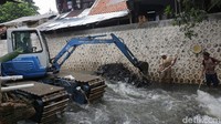 Tampak satu alat berat dikerahkan untuk mengangkat endapan lumpur dari dasar kali.