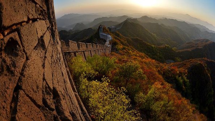 Nuansa Musim Gugur di Tembok Besar China This photo taken on October 20 shows the sun setting over the autumn colours of a section of the Great Wall of China at Jinshanling, Hebei Province. The wall which is a series of fortifications made of stone, brick and rammed earth was subject to a recent archaeological survey that found its total length to be 21,196 km or 13,171 miles. AFP PHOTO/Mark RALSTON (Photo by Mark RALSTON and - / AFP) (Photo by MARK RALSTON/AFP via Getty Images)