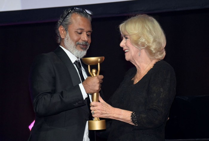 LONDON, ENGLAND - OCTOBER 17: Camilla, Queen Consort presents winner Shehan Karunatilaka for The Seven Moons of Maali Almeida with the Booker Prize for Fiction 2022 award at the Roundhouse, on October 17, 2022, in London, England. (Photo by Toby Melville - WPA Pool/Getty Images)