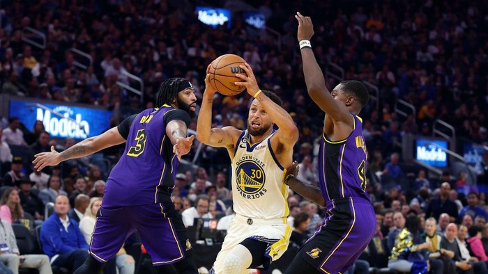 SAN FRANCISCO, CALIFORNIA - OCTOBER 18:  Stephen Curry #30 of the Golden State Warriors drives toward the basket as Lonnie Walker IV #4 and Anthony Davis #3 of the Los Angeles Lakers defend during the 1st half of the game at Chase Center on October 18, 2022 in San Francisco, California. NOTE TO USER: User expressly acknowledges and agrees that, by downloading and or using this photograph, User is consenting to the terms and conditions of the Getty Images License Agreement. (Photo by Ezra Shaw/Getty Images)