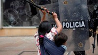 Seorang wanita pribumi yang menggendong anak bentrok dengan polisi anti huru hara di Bogota, Kolombia, 19 Oktober 2022.
