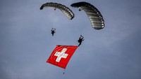 Pasukan terjun payung dari Angkatan Udara Swiss menunjukkan bendera saat acara live fire tahunan.  