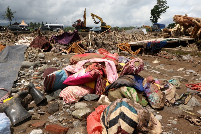 Barang-barang milik warga yang berserakan di jalanan akibat tersapu oleh banjir. Tampak barang yang tersapu tersebut terdiri dari bantal dan juga kain.