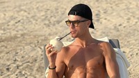 Liburan di pantai Dubai, Cristiano Ronaldo menikmati pemandangan. Momennya semakin lengkap sambil menyeruput air kelapa langsung dari batoknya!