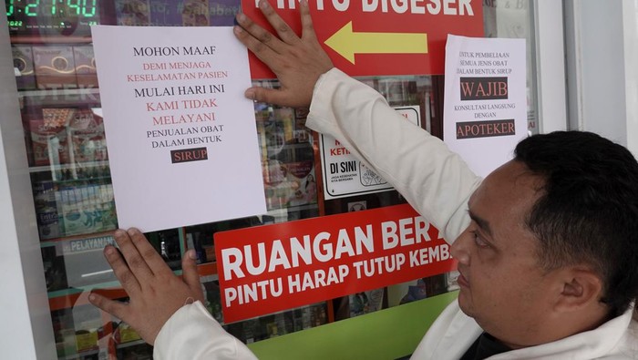 Apoteker memasang pengumuman penghentian penjualan  obat sirop, di Apotek Samudra Farma, Purwokerto, Banyumas, Jateng, Jumat (21/10/2022). Ikatan Apoteker Indonesia (IAI) Banyumas menghentikan penjualan semua produk obat sirop setelah mendapat instruksi dari Kemenkes dan mengembalikan lima produk yang sudah terindikasi berbahaya sesuai temuan BPOM kepada distributor.ANTARA FOTO/Idhad Zakaria/hp.