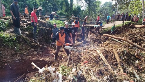 Petugas BPBD Tabanan dan Polsek Penebel membersihan sampah kayu yang membuat jebolnya jembatan penghubung Desa Senganan dan Biaung, Kecamatan Penebel, Jumat (21/10/2022).