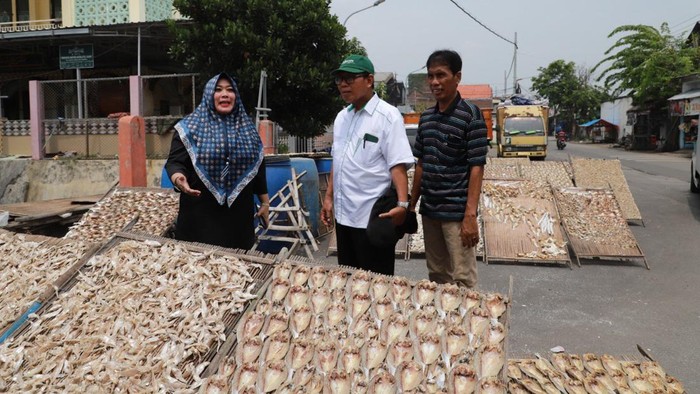 Nelayan menjemur ikan di jalan raya.