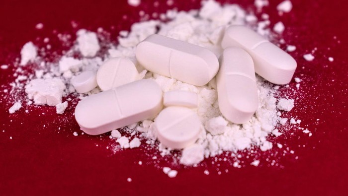 Crushed pills on a red background. Drug abuse. Close-up