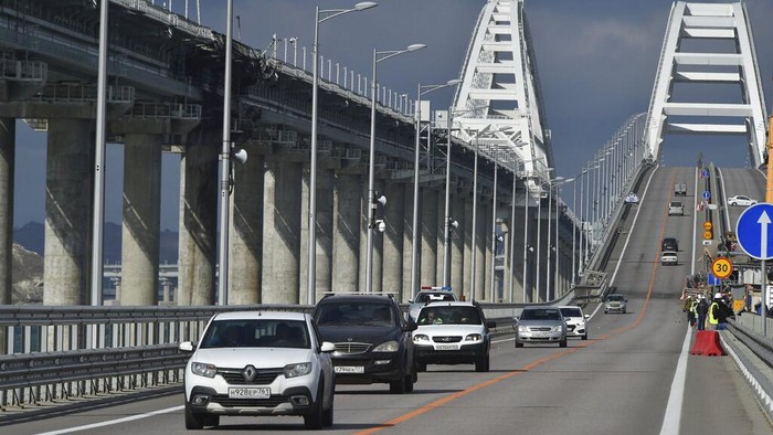Cars drive along parts of an automobile link of the Crimean Bridge connecting Russian mainland and Crimean peninsula over the Kerch Strait during restoration works, not far from Kerch, Crimea, Thursday, Oct. 20, 2022. The bridge, which holds important strategic and symbolic value to Russia was damaged by a truck bomb on Oct. 8, 2022 that cut one of its two automobile links. (AP Photo)