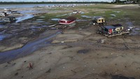 Akibat air surut, rumah perahu dan sampah kecil terdampar di daratan.