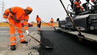 Pekerja membuat aspal baru di jalan raya A4 Turin, Italia, Kamis (20/10/2022).