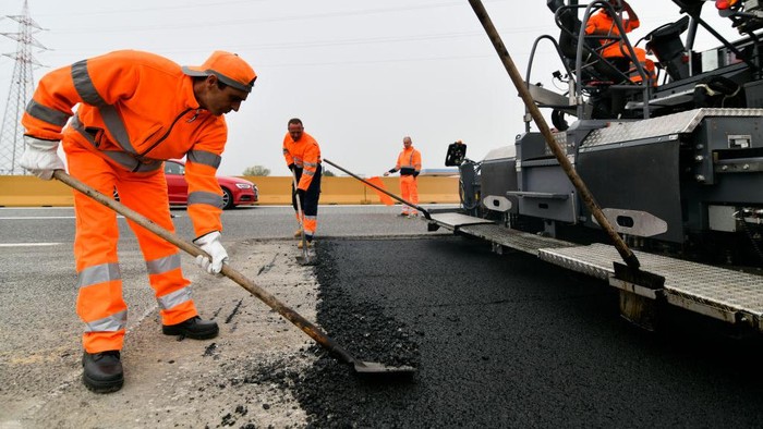 Pekerja membuat aspal baru di jalan raya a4 Turin, Italia, Kamis (20/10/2022).