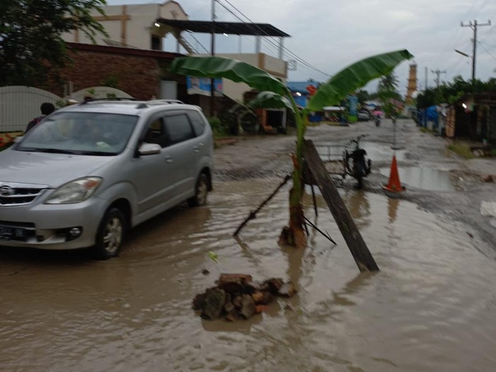 Warga menanam pohon pisang ditengah lubang yang tertutup genangan air di Kecamatan Buntu Pane, Kabupaten Asahan. (Istimewa).
