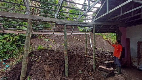 Kadek Rai Suastika (42) saat dijumpai pada Sabtu (21/10/2032), menunjukkan ketinggian tanah saat menyadari longsor menjebol dinding rumahnya di Banjar Piling Tengah, Desa Mangesta, Kecamatan Penebel, Tabanan, Bali. (chairul amri simabur/detikBali)