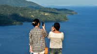 Sejumlah warga mengabadikan keindahan alam dengan gawai dari atas bukit paralayang Desa Airlouw, Kota Ambon, Provinsi Maluku, Sabtu (22/10/2022).