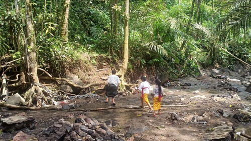 Sejumlah siswa dan warga menyeberangi sungai lantaran akses jalan Banyu Campah-Kebung, Kecamatan Sidemen, Kabupaten Karangasem, Bali, jebol. (Foto: I Wayan Selamat Juniasa/detikBali)