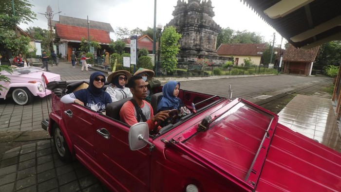 Wisatawan menaiki mobil Volkswagen (VW) dengan latar belakang Candi Pawon di Magelang, Jawa Tengah, Jumat (21/10/2022). Wisata menyusuri desa di lereng pegunungan Menoreh menggunakan mobil klasik tersebut menawarkan pemandangan pedesaan dan sejumlah candi dengan harga Rp400 ribu hingga Rp1 juta per paket. ANTARA FOTO/Prasetia Fauzani/nz