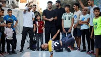 Anak-anak hingga remaja melakukan gerakan breakdance di jalan kamp pengungsi Nusseirat Jalur Gaza tengah. Tarian yang pernah dikutuk oleh beberapa penduduk setempat sebagai tidak bermoral, sekarang dipandang sebagai cara untuk membantu anak-anak muda mengatasi trauma perang selama bertahun-tahun.