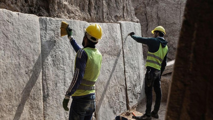 Pahatan Kuno Berusia Ribuan Tahun Selamat dari Gempuran Isis, Begini Rupanya Iraqi workers excavate a rock-carving relief recently found at the Mashki Gate, one of the monumental gates to the ancient Assyrian city of Nineveh, on the outskirts of what is today the northern Iraqi city of Mosul on October 19, 2022. (Photo by Zaid AL-OBEIDI / AFP) (Photo by ZAID AL-OBEIDI/AFP via Getty Images)