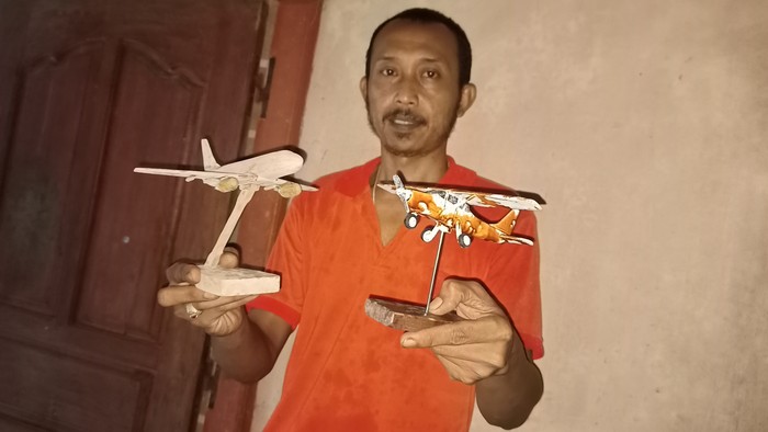 Rai Suastika dengan miniatur pesawat yang dibuat dari limbah kayu hasil kreasinya. (chairul amri simabur/detikBali)