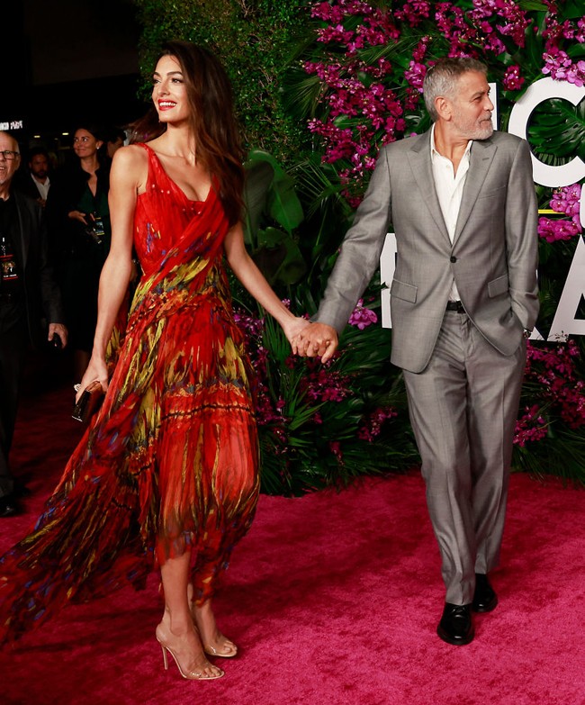 Wanita yang berprofesi sebagai pengacara hak asasi manusia itu terlihat membawa clutch gold dan memakai high heels PVC transparan serta perhiasan Cartier untuk membuat penampilannya terlihat glamour. Foto: Michael Tran/AFP/Getty Images