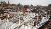 Seorang petugas membereskan puing-puing di atas genteng. Angin puting beliung tersebut menerjang Sidoarjo pada hari Minggu (23/10).