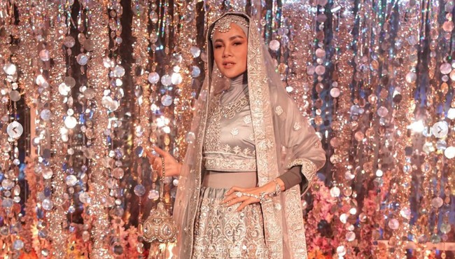 Olla Ramlan tampil berhijab dan menyulap baju tradisional India yang dikenakannya terlihat lebih syar’i. Sang aktris memakai manset di balik atasan crop top abu-abu dan membawa tas kecil serasi yang mengkilap. Foto: Instagram