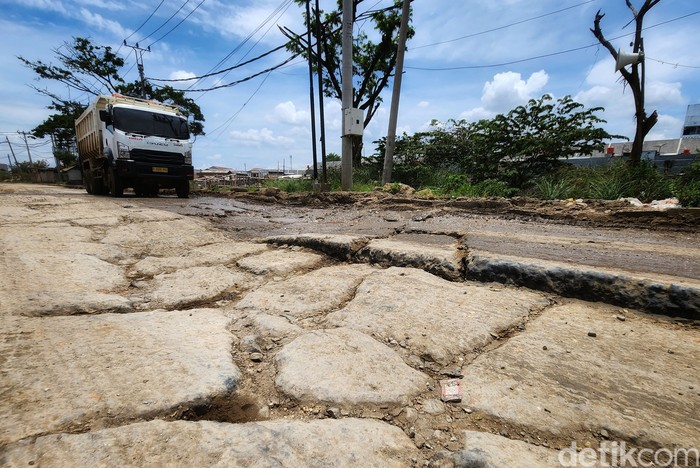 Mobil pribadi dan truk melintas di Jalam Perancis, Dadap, Kosambi, Tangerang, Senin (24/10/2022). Jalan yang sudah dibeton tersebut terpantau rusak parah dalam beberapa bulan terakhir. Jika hujan, jalanan menjadi kubangan lumpur dan saat matahari terik diselimuti debu.