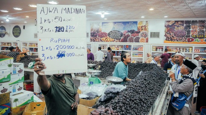 Penjual menunjukkan papan harga kurma yang dijual di toko Kebun Kurma, Madinah, Arab Saudi, Minggu (23/10/2022). Papan yang dipegang oleh penjual bertuliskan harga perkilo kurma dalam bentuk rupiah.