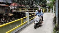 Pengendara sepeda motor melintas di samping pagar Kali Mampang yang telah diperbaiki, Senin (24/10/2022).