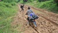 Warga Suku Talang Mamak mengendarai sepeda motor melintasi jalan rusak di Dusun Semerantihan, Sumay, Tebo, Jambi, Minggu (23/10/2022).