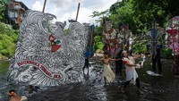 Seniman menunjukan aksinya saat pementasan wayang bertajuk Air Mata Air di bawah Jembatan Wreksodiiningrat, Kali Code.