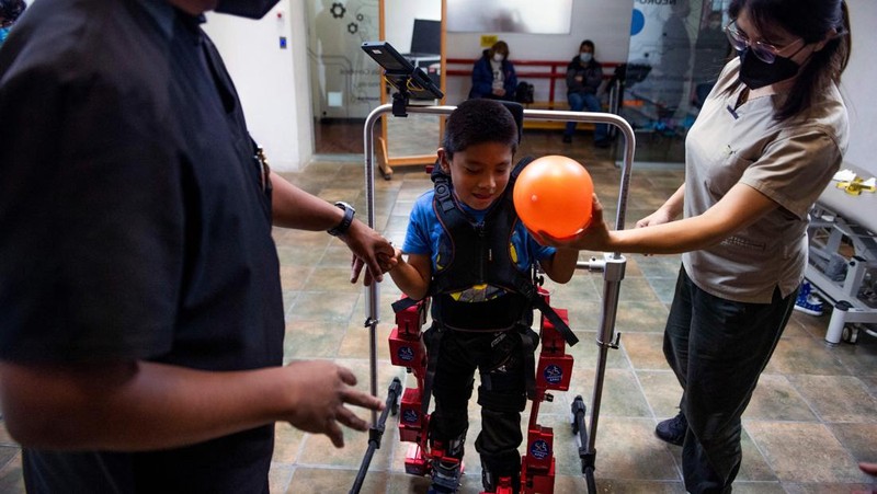 David Zabala (C), an 8-year-old boy with cerebral palsy, is assisted by physical therapists during a rehabilitation session with the robotic exoskeleton Atlas 2030 at the Association for People with Cerebral Palsy (APAC) in Mexico City on October 18, 2022. - The Atlas 2030 pediatric exoskeleton, which won its creator, Spanish Elena García Armada, the 2022 European Inventor award, has been in use in Mexico since October, thanks to the efforts of the Association for People with Cerebral Palsy (APAC), a private organisation founded in 1970. (Photo by CLAUDIO CRUZ / AFP) (Photo by CLAUDIO CRUZ/AFP via Getty Images)