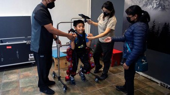 David Zabala, anak laki-laki berusia 8 tahun dengan Cerebral Palsy, dibantu oleh ahli terapi fisik selama sesi rehabilitasi dengan robot exoskeleton Atlas 2030 di Association for People with Cerebral Palsy (APAC) di Mexico City, Meksiko, Selasa (18/10/2022).  