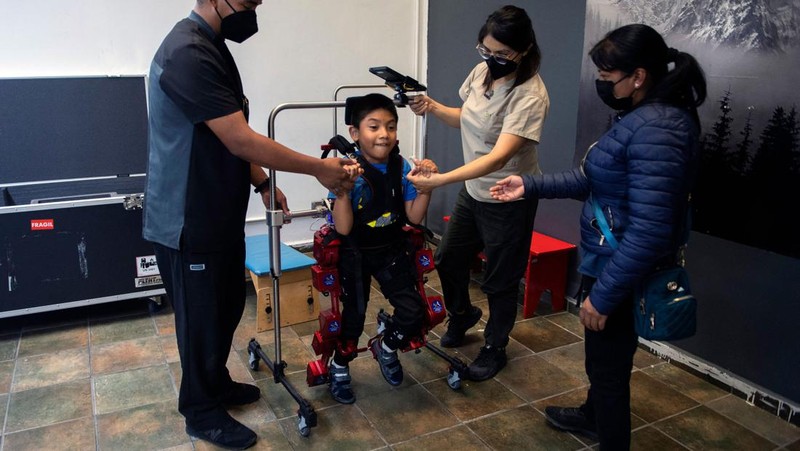 David Zabala (C), an 8-year-old boy with cerebral palsy, is assisted by physical therapists during a rehabilitation session with the robotic exoskeleton Atlas 2030 at the Association for People with Cerebral Palsy (APAC) in Mexico City on October 18, 2022. - The Atlas 2030 pediatric exoskeleton, which won its creator, Spanish Elena García Armada, the 2022 European Inventor award, has been in use in Mexico since October, thanks to the efforts of the Association for People with Cerebral Palsy (APAC), a private organisation founded in 1970. (Photo by CLAUDIO CRUZ / AFP) (Photo by CLAUDIO CRUZ/AFP via Getty Images)