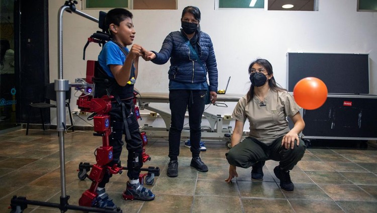 Canggihnya Kerangka Robot yang Bantu Terapi Anak Lumpuh di Meksiko David Zabala (C), an 8-year-old boy with cerebral palsy, is assisted by physical therapists during a rehabilitation session with the robotic exoskeleton Atlas 2030 at the Association for People with Cerebral Palsy (APAC) in Mexico City on October 18, 2022. - The Atlas 2030 pediatric exoskeleton, which won its creator, Spanish Elena García Armada, the 2022 European Inventor award, has been in use in Mexico since October, thanks to the efforts of the Association for People with Cerebral Palsy (APAC), a private organisation founded in 1970. (Photo by CLAUDIO CRUZ / AFP) (Photo by CLAUDIO CRUZ/AFP via Getty Images)
