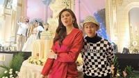 Kalau ini momen Clara menghadiri acara pernikahan rekannya. Ia berpose di depan kue pengantin bernuansa putih yang cantik dan menjulang.
