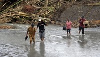 Perangkat desa dan warga menyeberangi sungai pascabanjir bandang di Dusun Sekar Kejula Kelod, Desa Yehembang Kauh, Jembrana, Bali, Selasa (25/10/2022).