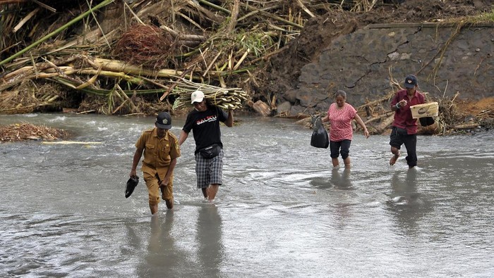 Jembatan Ambruk Akibat Banjir, Warga Jembrana Terpaksa Lintasi Sungai Perangkat desa dan warga menyeberangi sungai pascabanjir bandang di Dusun Sekar Kejula Kelod, Desa Yehembang Kauh, Jembrana, Bali, Selasa (25/10/2022). Sejak jembatan beton penghubung empat dusun yakni Dusun Sekar Kejula Kelod, Dusun Sekar Kejula, Dusun Kedisan, dan Dusun Munduk Anggrek tersebut ambruk akibat diterjang banjir bandang yang terjadi pada Minggu (16/10) lalu, banyak siswa dan warga memilih menyeberang sungai dengan berjalan kaki saat menuju sekolah maupun kantor desa menyusul jauhnya jarak jalur alternatif di dusun itu. ANTARA FOTO/Nyoman Hendra Wibowo/hp.