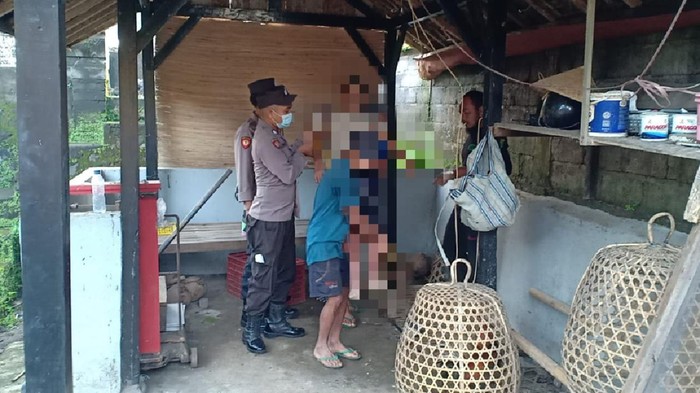 Petugas kepolisian bersama keluarga saat menurunkan jenazah INM yang tergantung di gudang, untuk dibawa ke rumahnya, Desa Sangkan Gunung, Kecamatan Sidemen, Kabupaten Karangasem, Bali, Selasa (25/10/2022).