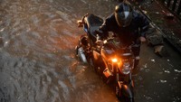 Seorang pengendara mendorong motornya di tengah banjir dan hujan yang mengguyur kota Dhaka. (Syed Mahamudur Rahman/Getty Images)