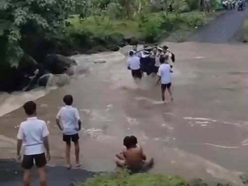 Tangkapan layar siswa SMPN 3 Amlapura gotong royong mengangkat sepeda motor untuk menyeberang jalan yang dialiri air sungai yang meluap