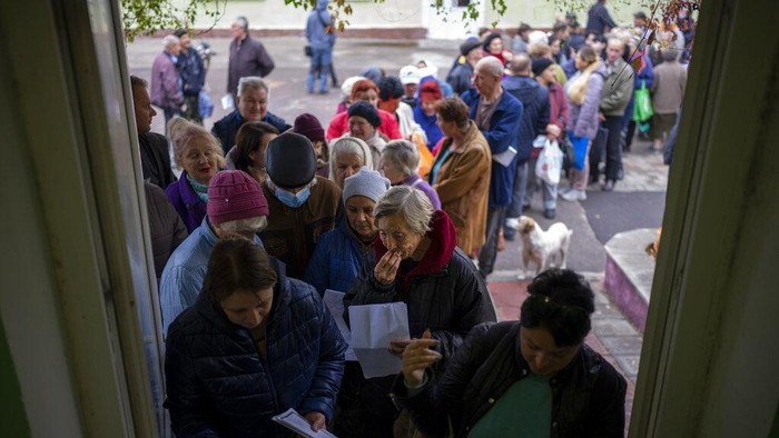 People queue to receive a daily ration of bread in a school in Mykolaiv, Tuesday, Oct. 25, 2022. Mykolaiv residents pick up bread from the only food distribution point in Varvarivka, a Mykolaiv district where thousands of people live. One person is allowed to receive free bread just once in three days. (AP Photo/Emilio Morenatti)