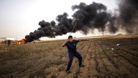 Seorang pria Palestina melemparkan batu ke arah pasukan Israel di Tepi Barat, Gaza, Palestina, Selasa (25/10/2022).  