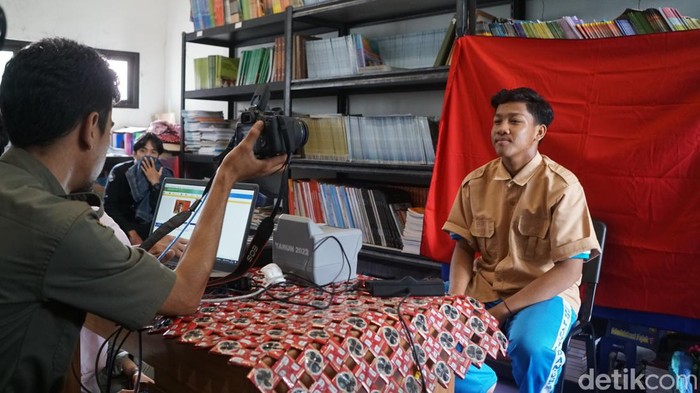 Siswa melakukan sesi pemotretan dengan latar background berwarna merah. Sejak bulan Oktober, Kecamatan Neglasari menjalani program Pelayanan Keliling Kependudukan Hebat dan Pelayanan Umum (Langkah Yanum) secara goes to school.